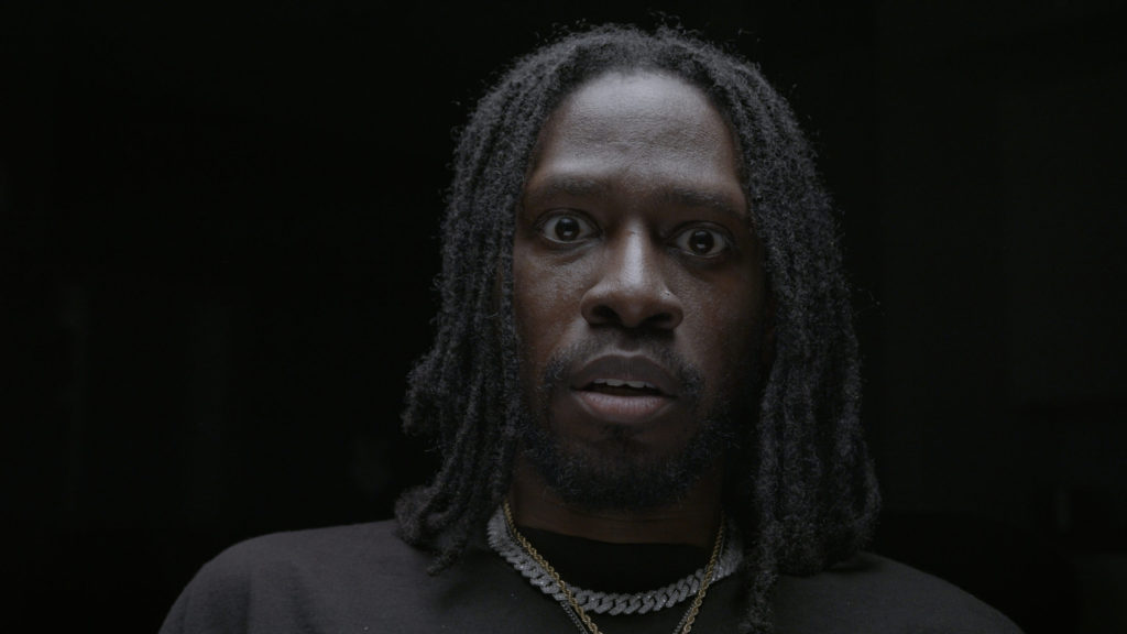 Close portrait of music artist against a dark background.