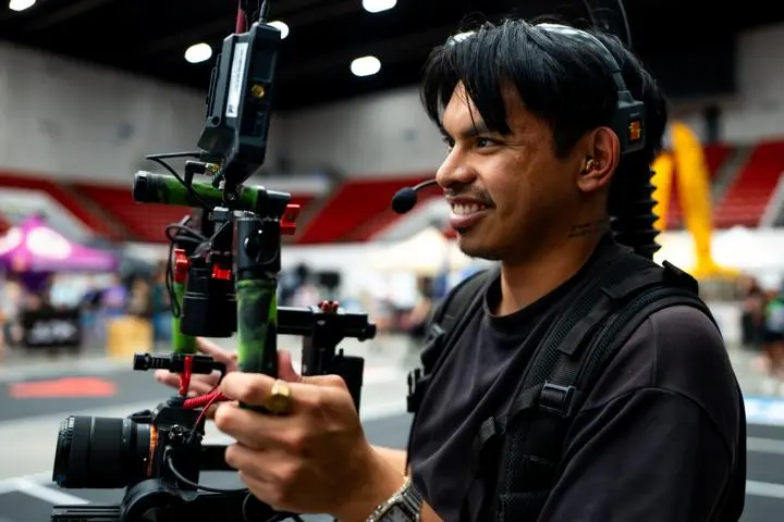 Aren Rosales smiling while holding a camera rig and wearing a headset