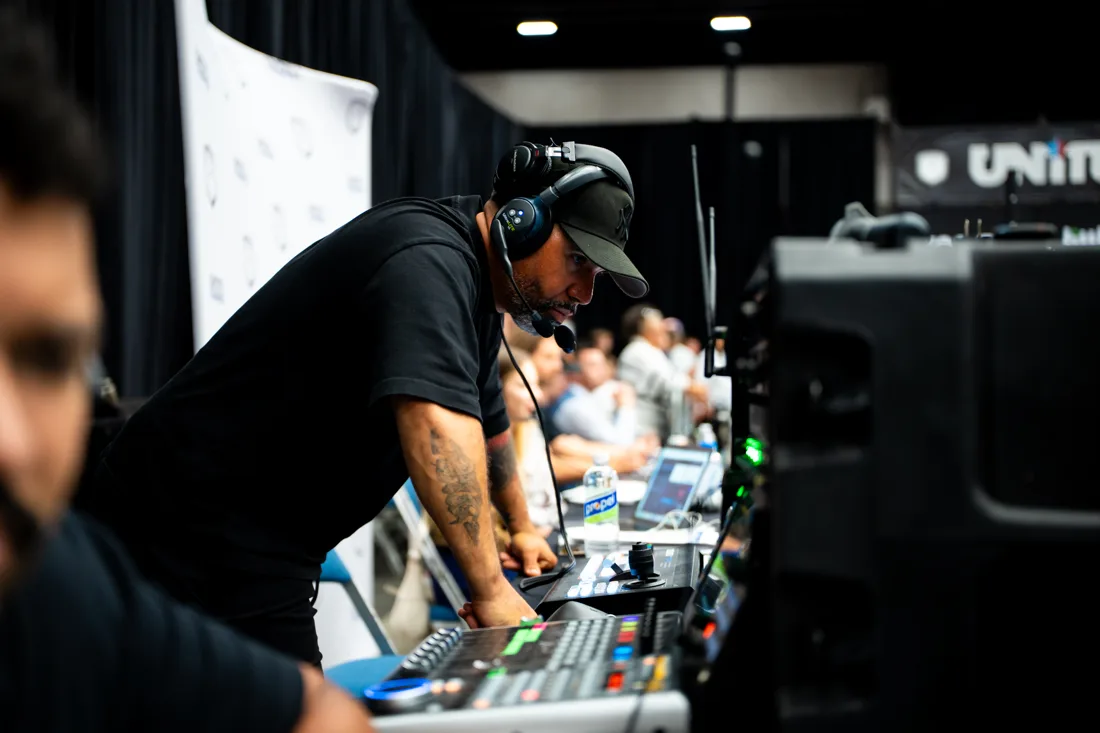 Jan-Michael Reyes leaning over the production table with broadcast equipment in view