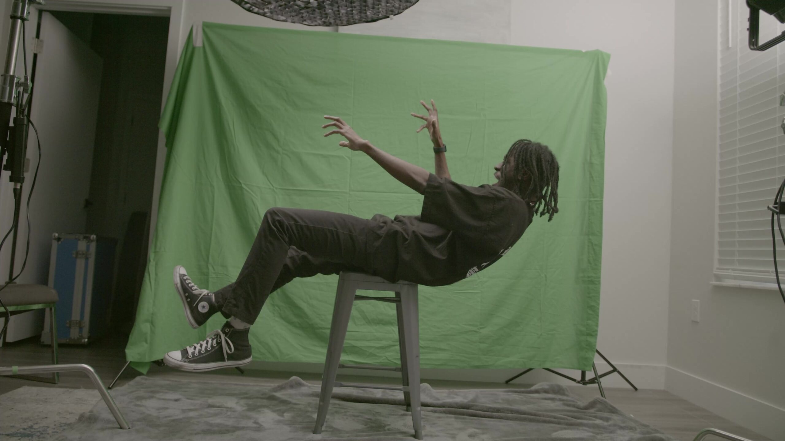 The supplied source clip shows the supported falling performance, the green backdrop, and the surrounding room. The stool must be addressed separately from the green.