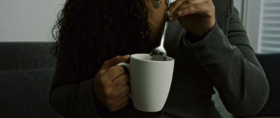 Close-up of a woman stirring a white cup in Haunted (2023)