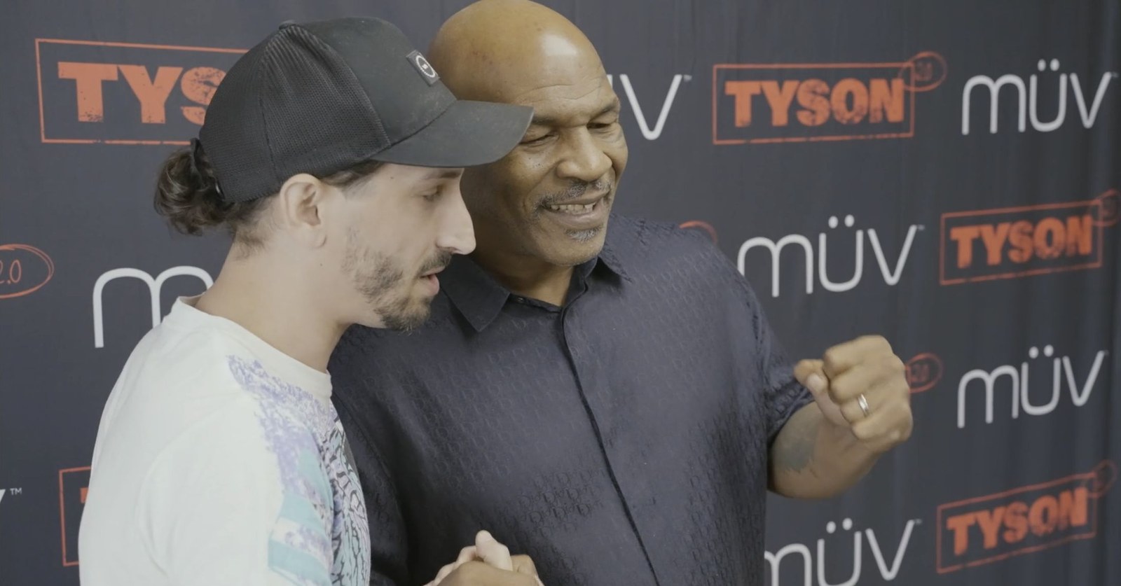 Mike Tyson with an attendee in front of the tour backdrop